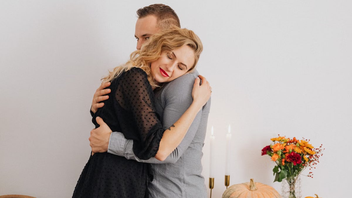 Couple sharing a hug with autumn decor in the background, symbolizing love and togetherness.